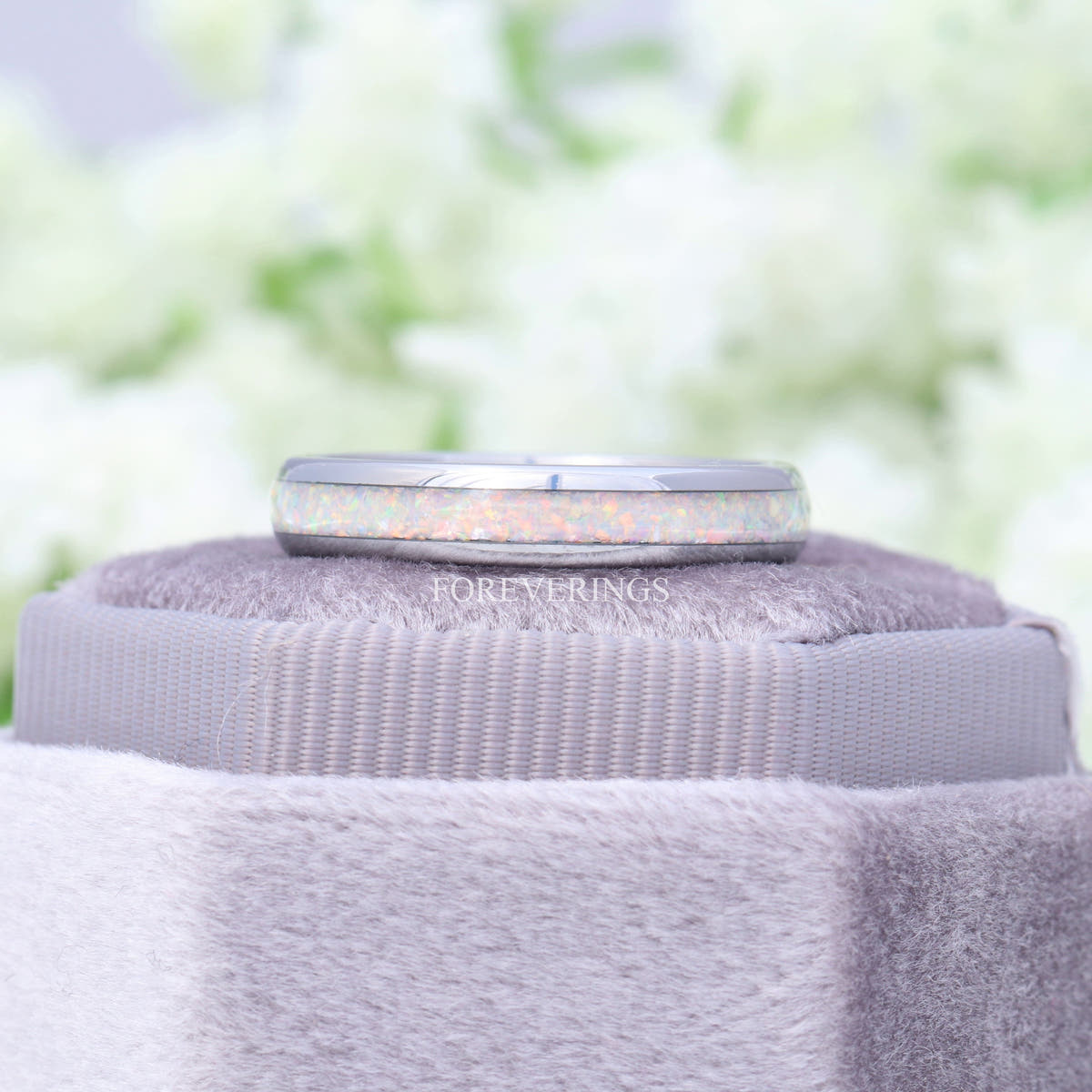 4mm white fire opal ring resting on top of a gray velvet ring box