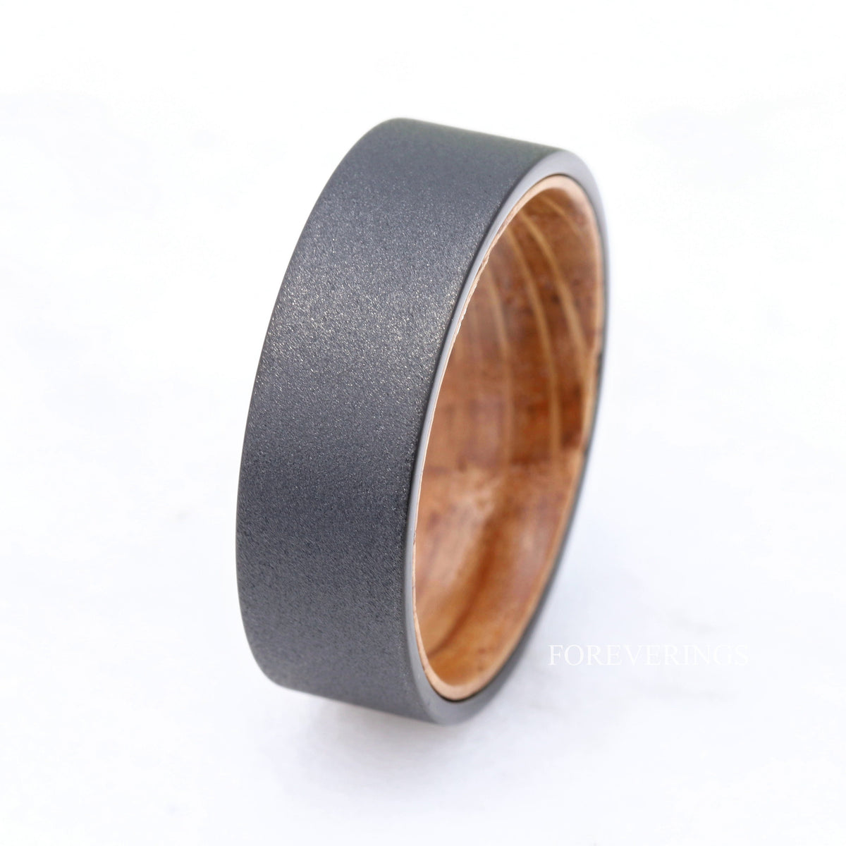 8mm black tungsten band turned at an angle to show its whiskey barrel wood lining