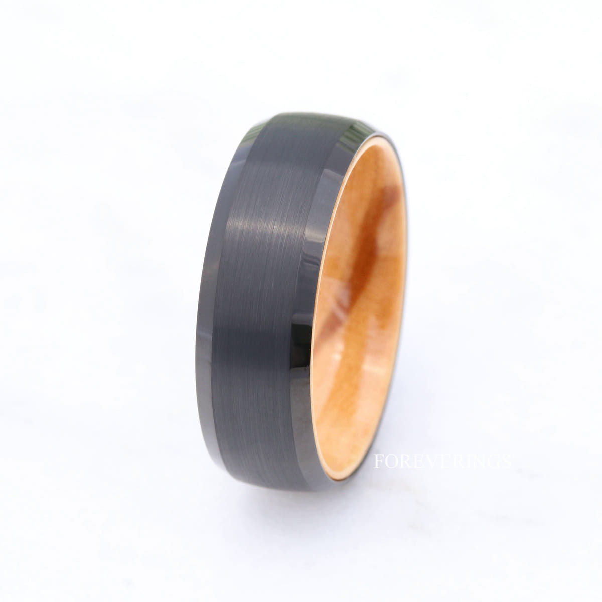 Brushed black tungsten and olive wood band standing on a white background