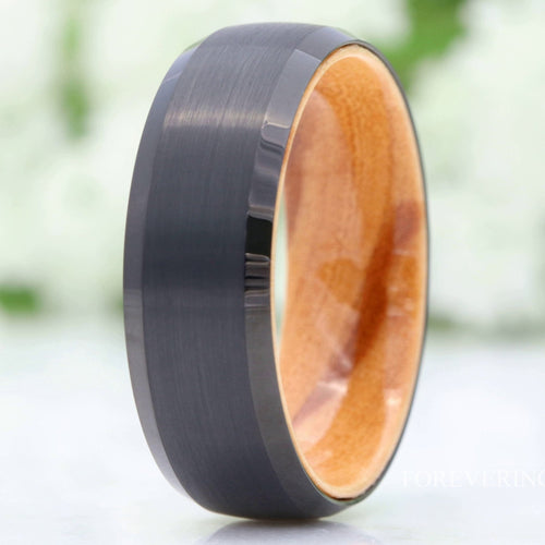 Men's 8mm brushed black tungsten band with olive wood interior, standing in a close crop