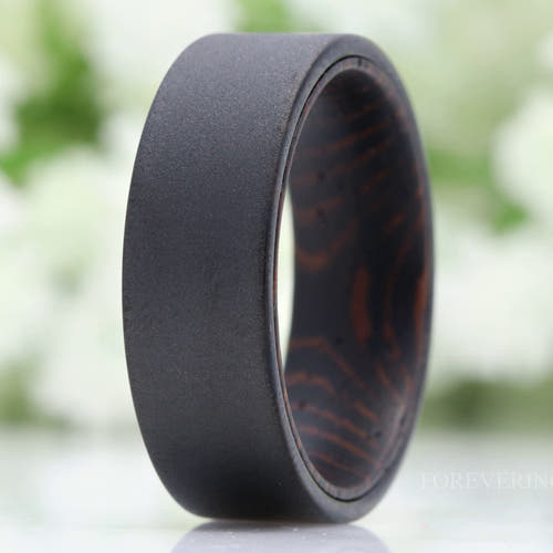 Men's 8mm sandblasted black tungsten wedding band with wenge wood lining, standing at an angle