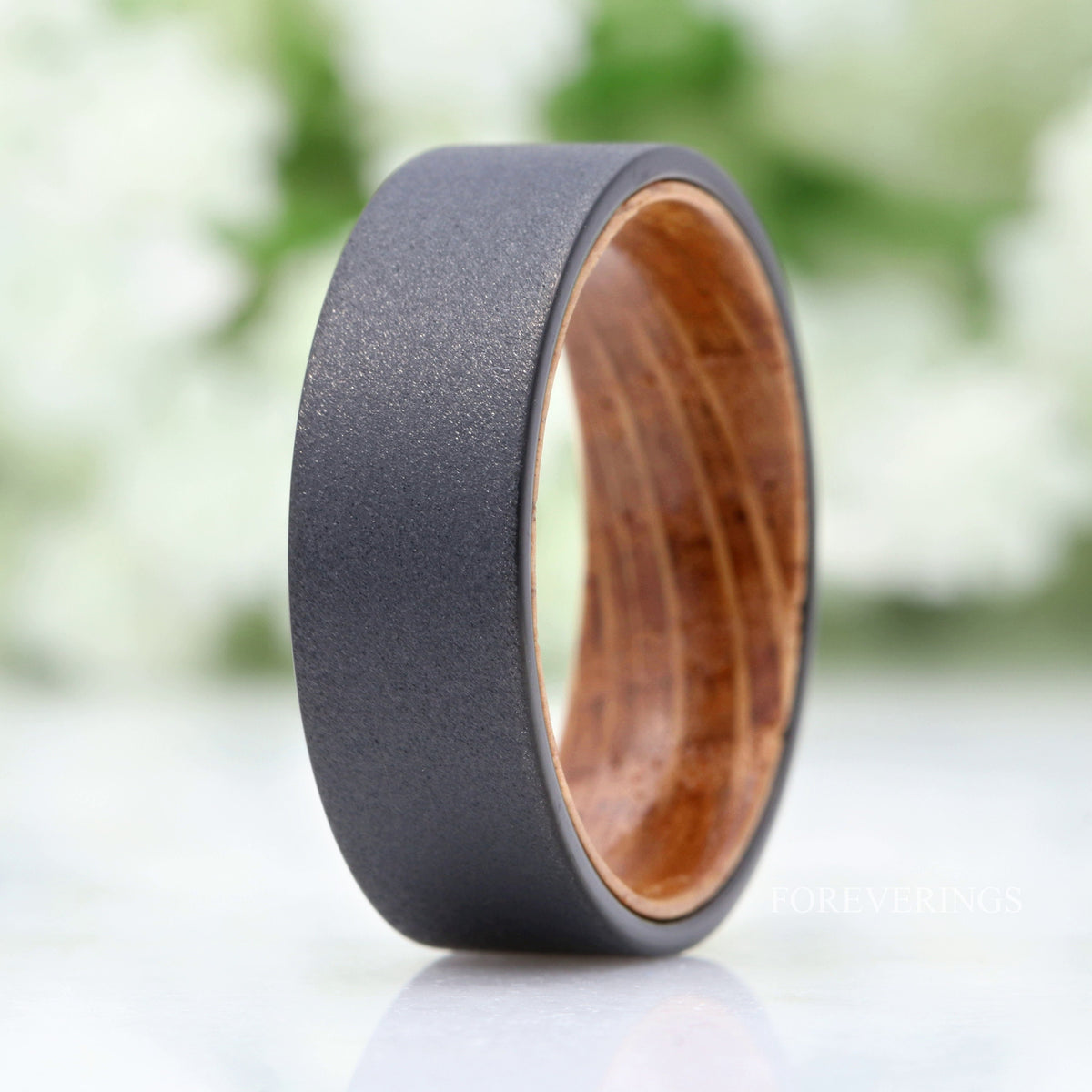 Closer crop of the black tungsten band standing upright, whiskey barrel wood grain inside