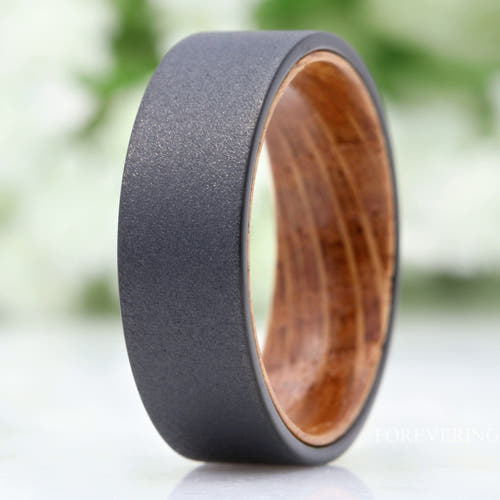 Men's 8mm sandblasted black tungsten wedding band with a whiskey barrel wood sleeve