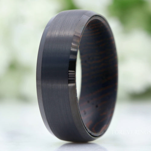 Men's 8mm brushed black tungsten wedding band with a wenge wood interior, standing on edge