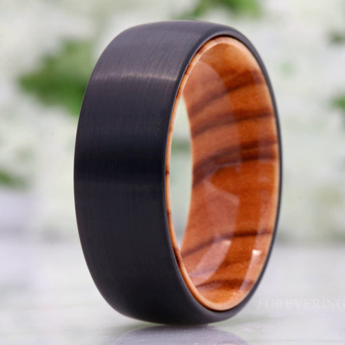 Men's 8mm matte black tungsten band with an olive wood interior, standing on edge