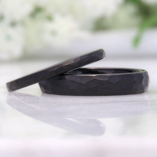 Hammered matte black tungsten wedding bands in 2mm and 4mm, leaning together