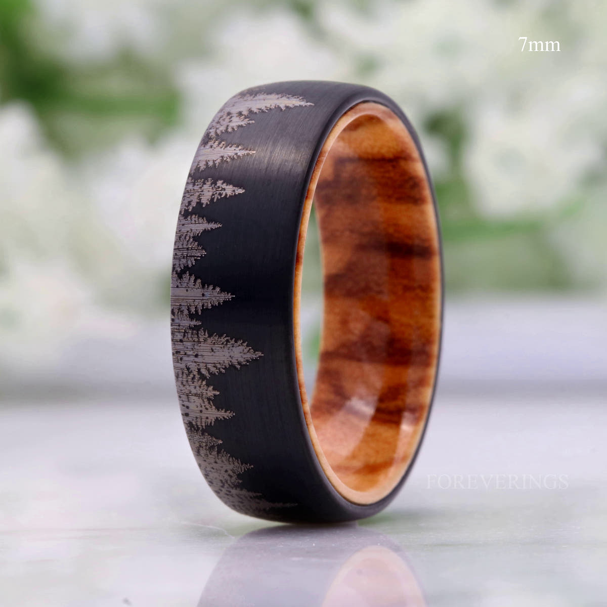 7mm black tungsten band with pine tree pattern and olive wood interior, standing upright