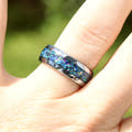 Men's 8mm silver tungsten galaxy opal ring worn on a finger