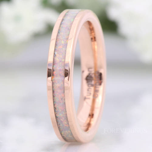 Women's 4mm rose gold tungsten ring with white fire opal inlay, standing on edge in a close crop