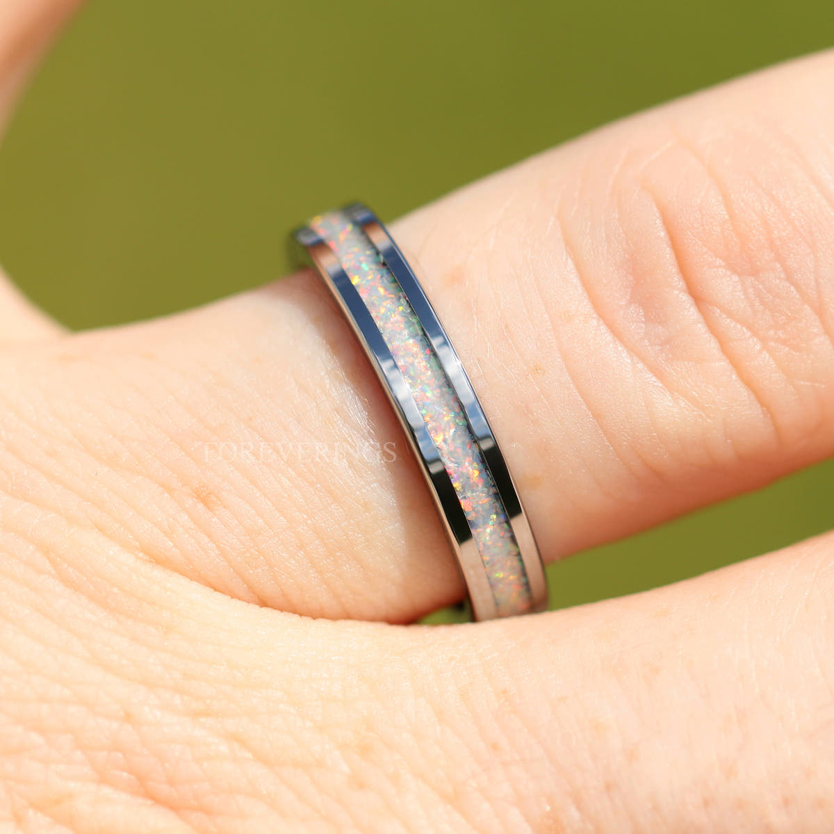Silver tungsten ring with crushed white fire opal worn on a hand, side view