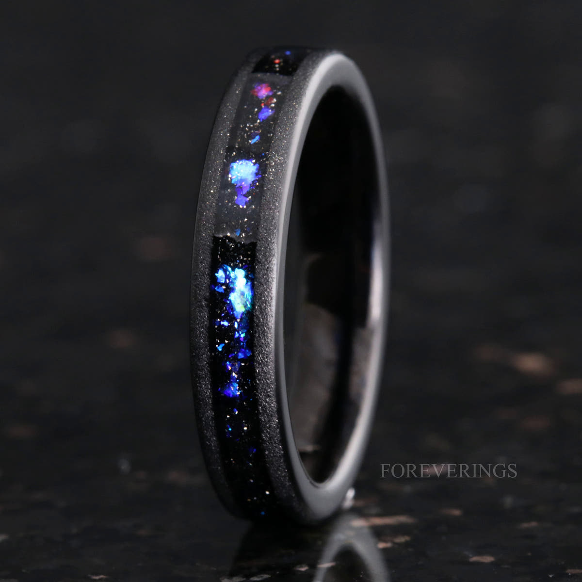 Women's 4mm black tungsten band with blue and purple sandstone inlay, standing upright in a closer view