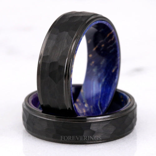 Men's hammered black tungsten band with blue elder wood lining, set upright on a second band