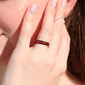Women's 4mm black tungsten ring with ruby inlay worn on a hand