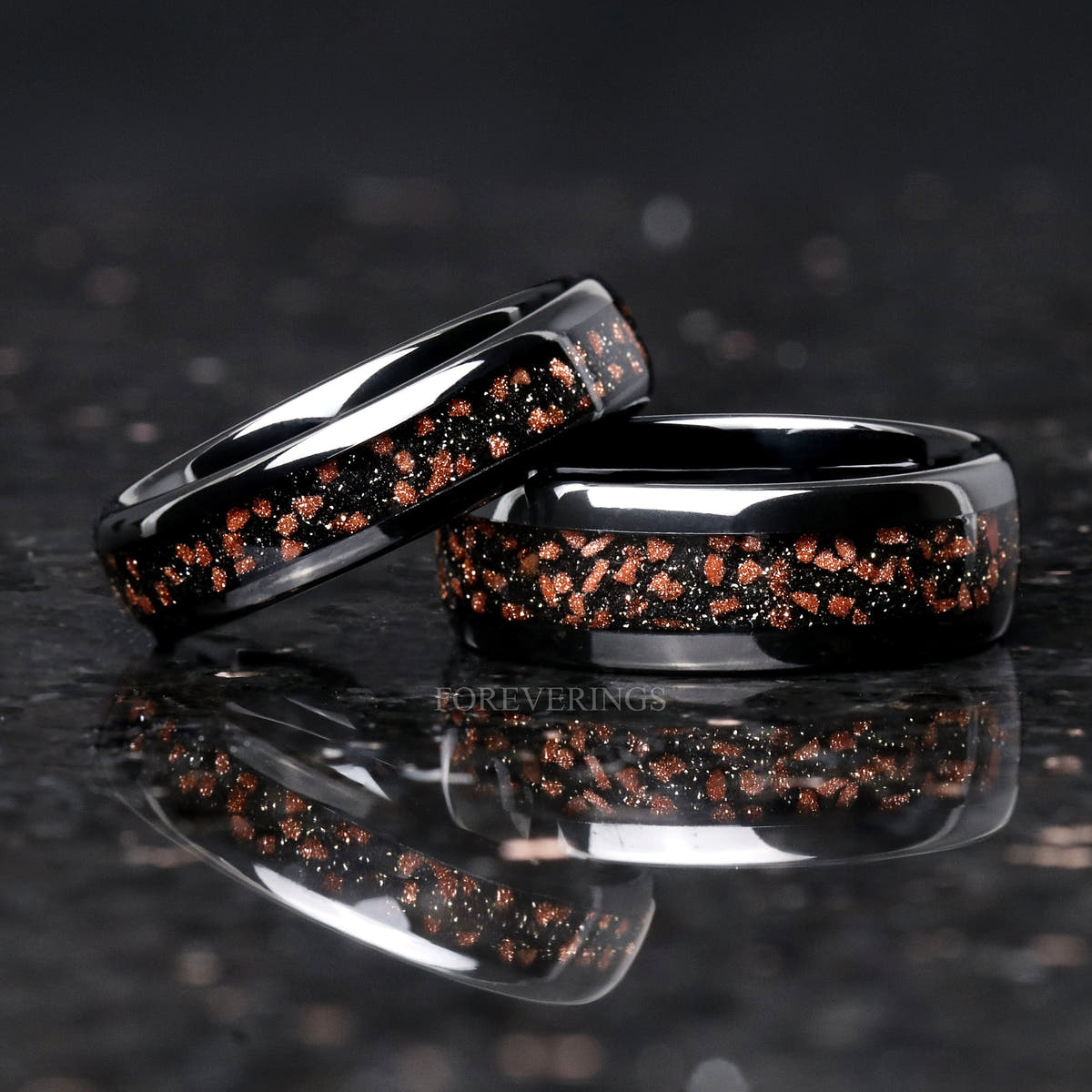 Two widths of the black tungsten red goldstone band, the narrower one tilted against the wider
