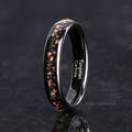 Her 4mm black tungsten ring with red goldstone inlay standing at an angle
