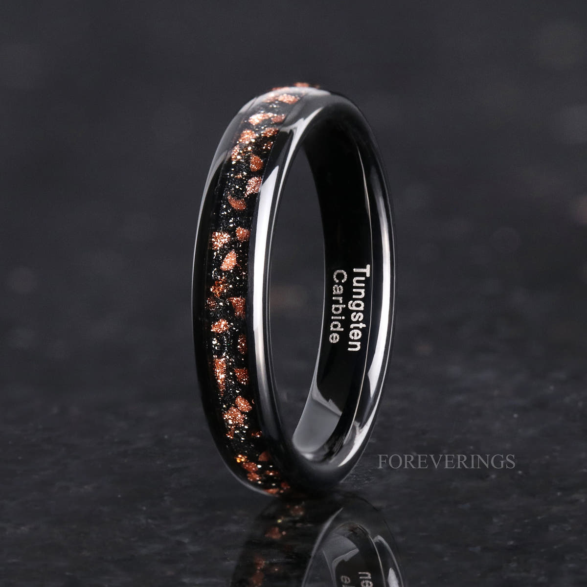 Her 4mm black tungsten ring with red goldstone inlay standing at an angle