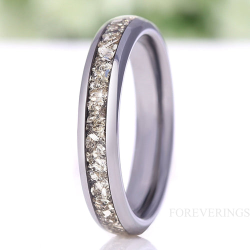 Women's 4mm silver tungsten wedding band with crushed diamond inlay, standing on edge in a close crop