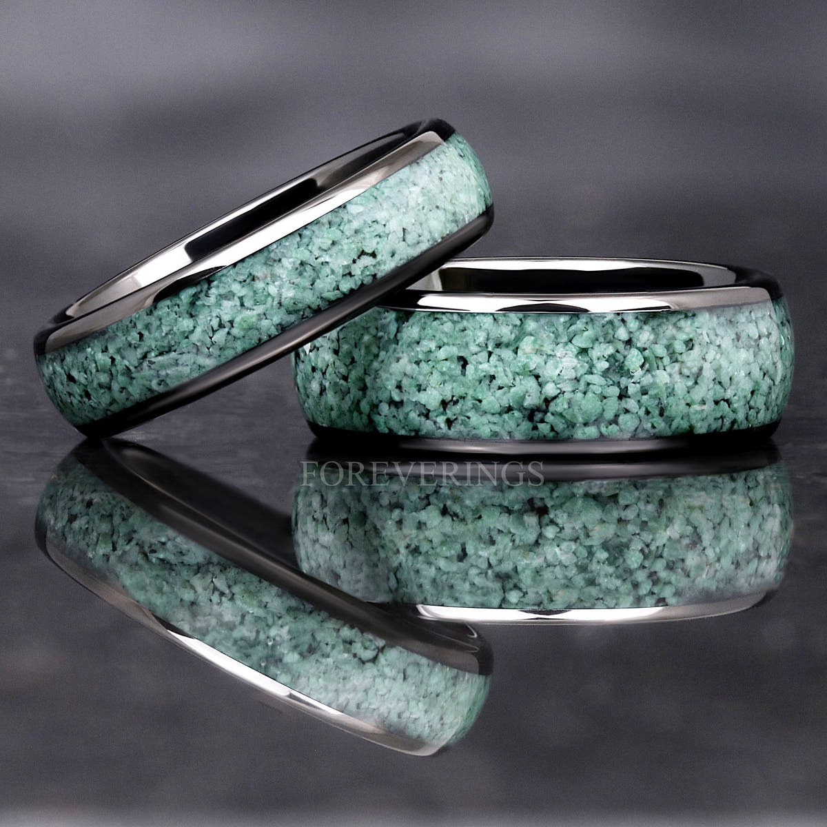 Narrow and wide black tungsten moss agate rings, one leaning on the other