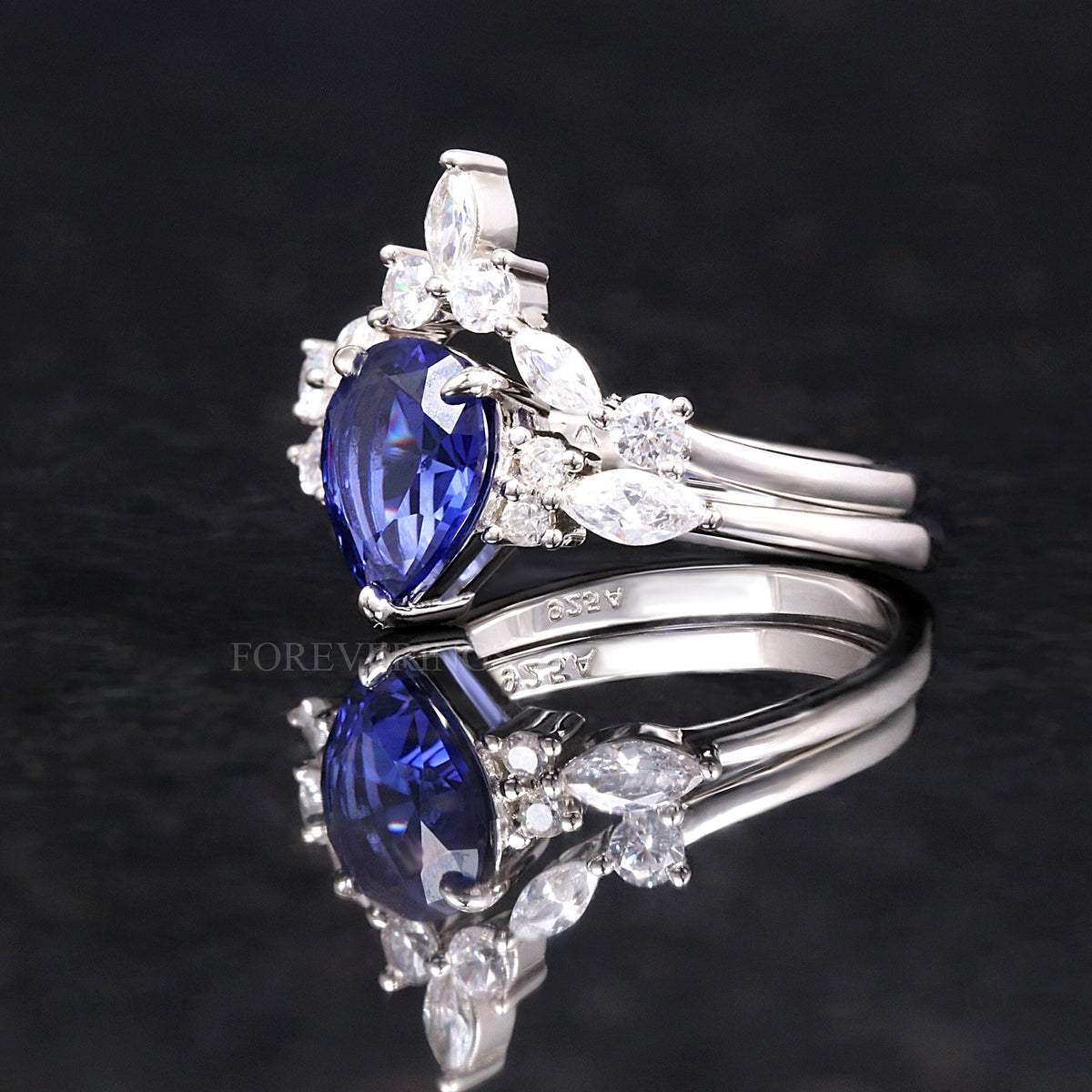 Pear-cut sapphire engagement ring and nesting band in sterling silver, angled side view