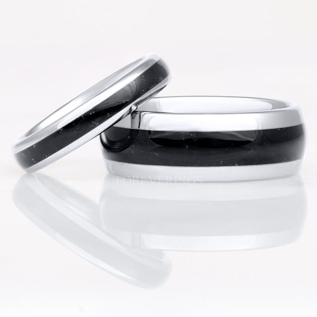 4mm silver tungsten ring with black onyx inlay leaning on a wider silver and black onyx band