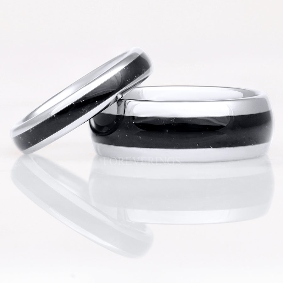 4mm silver tungsten ring with black onyx inlay leaning on a wider silver and black onyx band