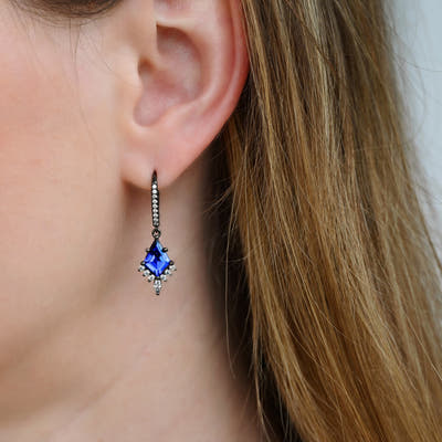 Black sterling silver blue sapphire drop earring worn on the ear, close-up