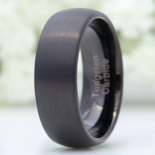 Men's 8mm brushed black tungsten wedding ring standing on edge, close crop