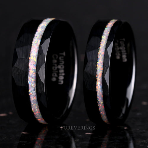 Two men's hammered black tungsten rings with an offset white fire opal stripe, standing upright