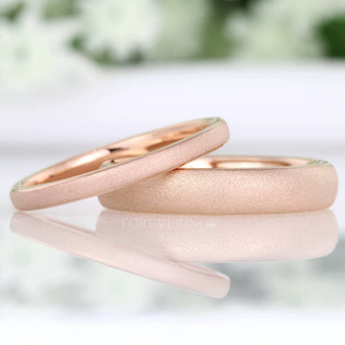 Sandblasted rose gold tungsten bands in 2mm and 4mm, one resting on the other