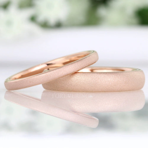 Sandblasted rose gold tungsten bands in 2mm and 4mm, one resting on the other