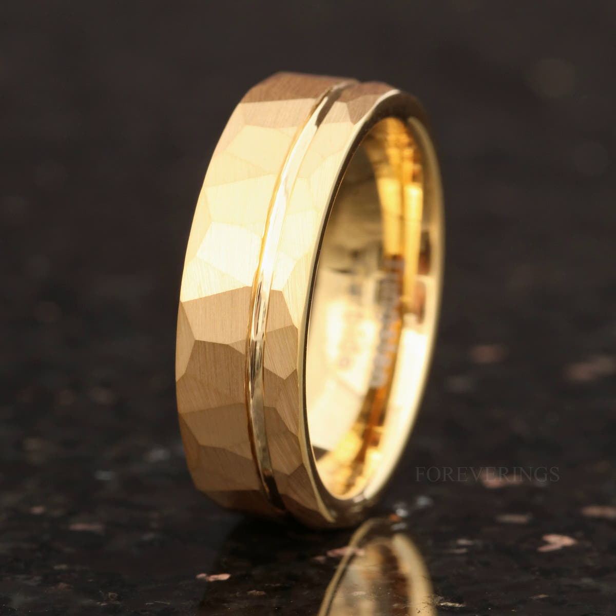 7mm gold tungsten band with hammered facets, standing at an angle, wider view