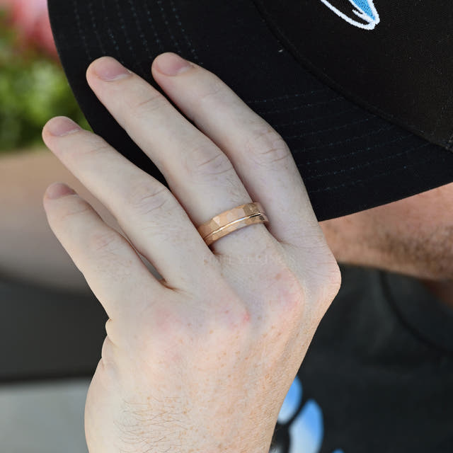 Hammered rose gold tungsten band with offset groove worn on a man's hand