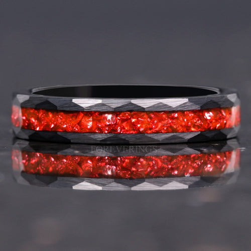4mm hammered black tungsten wedding band with crushed ruby inlay lying flat, reflection below