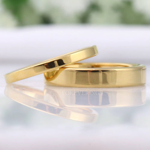 Men's and women's minimalist flat gold tungsten wedding bands in 2mm and 4mm, lying together