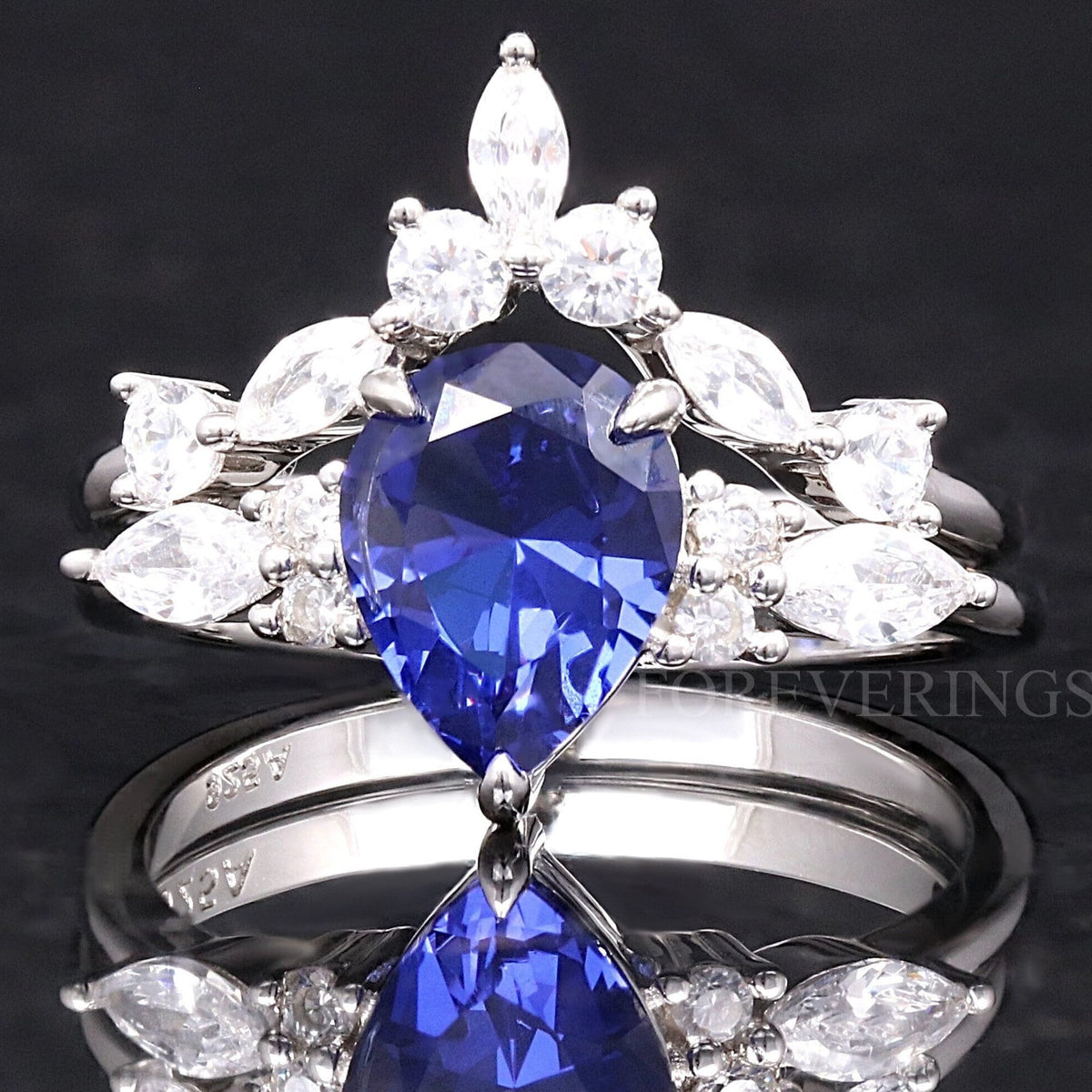 Women's sterling silver bridal set with a pear-cut sapphire and a curved marquise accent band, front view