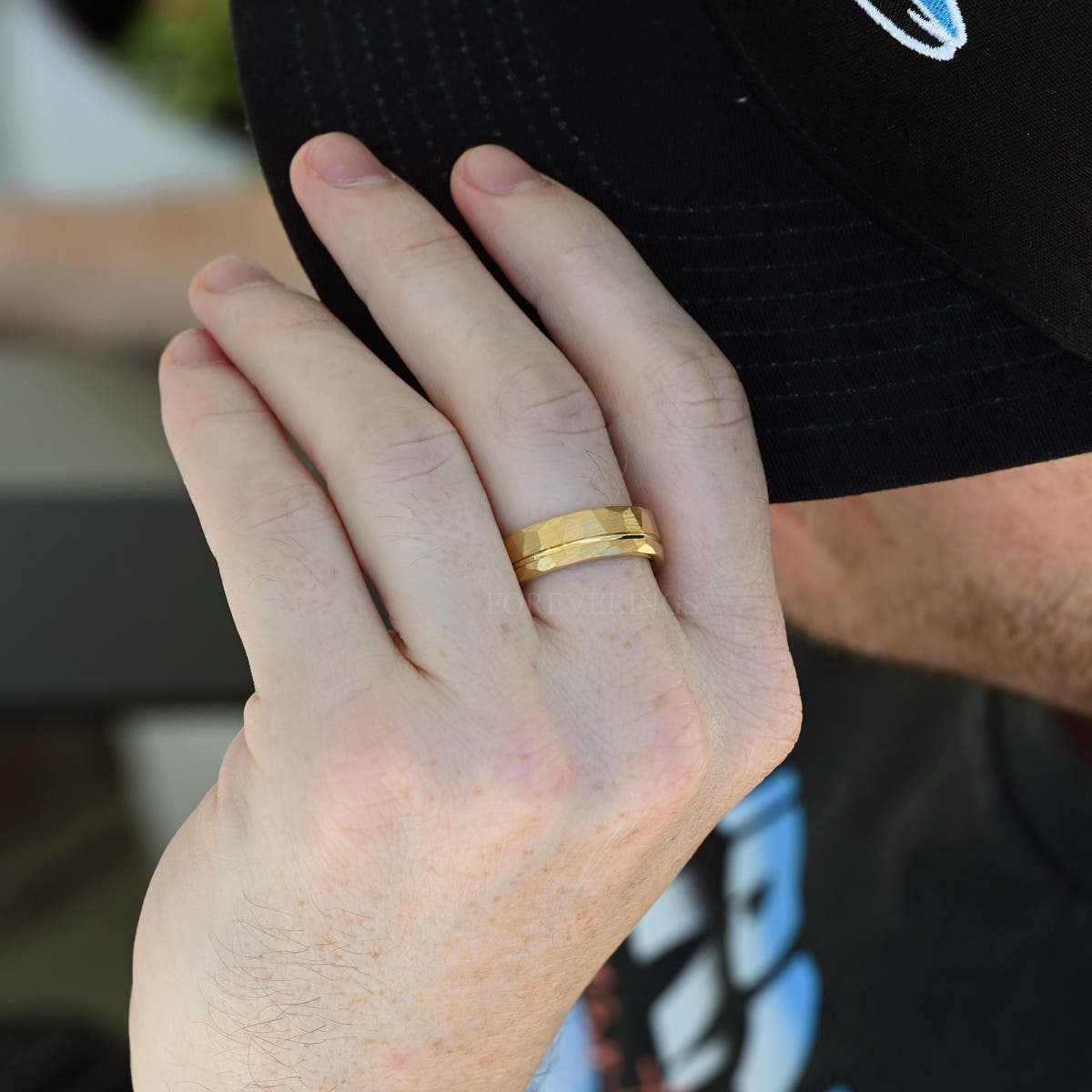 Men's 7mm hammered gold tungsten band worn on a man's hand