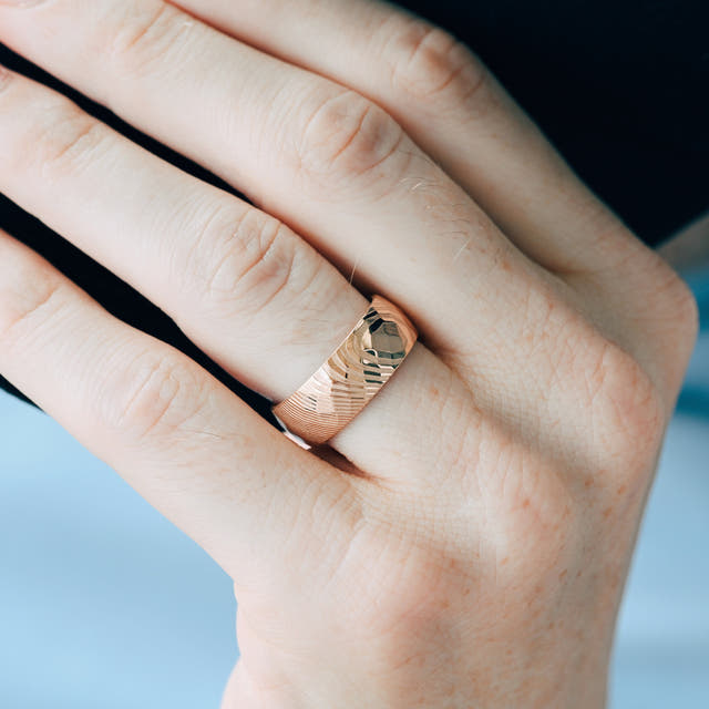 8mm rose gold Damascus steel wedding band worn on a man's hand