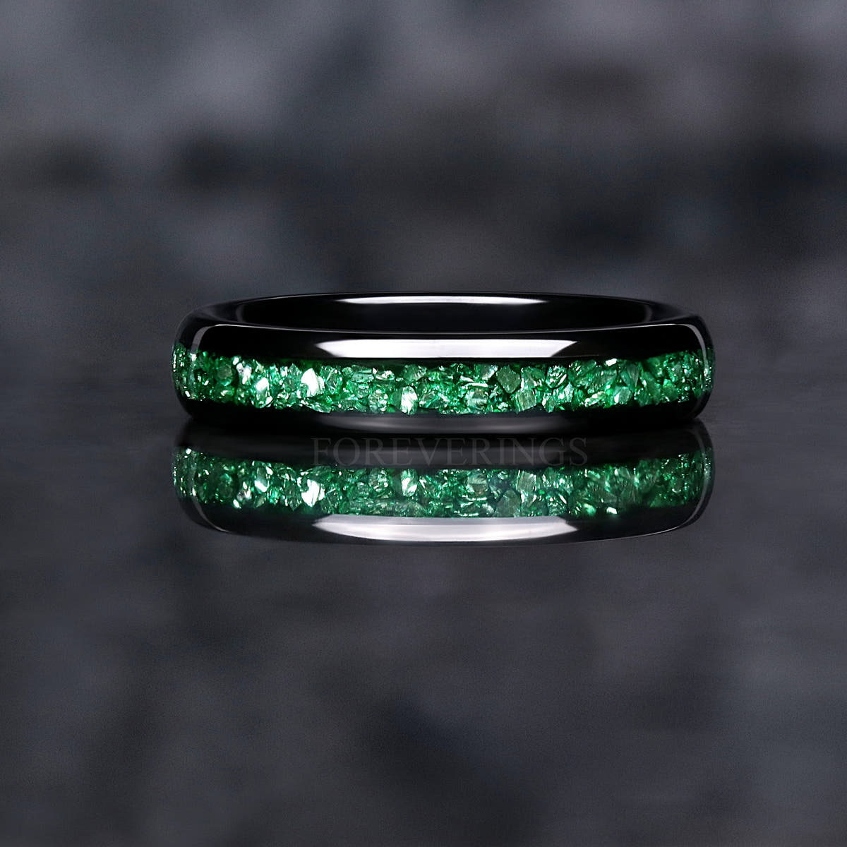 Black tungsten emerald inlay band shown straight on, green stones across the domed face