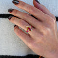 Women's gold ruby engagement ring worn on a hand, angled from above