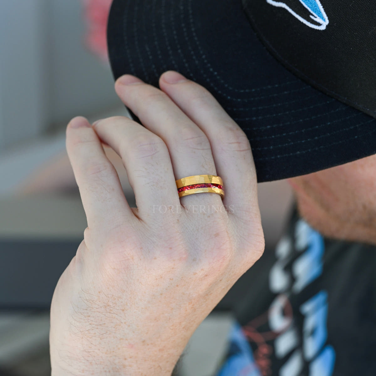 Men's gold tungsten band with a crushed ruby stripe worn on a hand