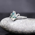 Sterling silver moss agate ring with twirl band at an angle, side view