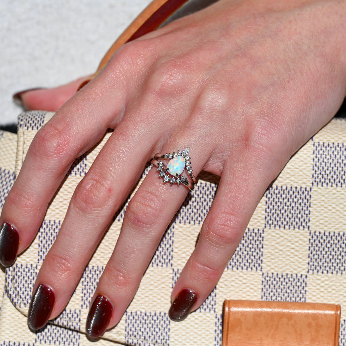 White fire opal engagement ring and crown band in sterling silver worn on a woman's hand