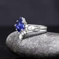 Kite-cut blue sapphire engagement ring and curved band in sterling silver, angled side view