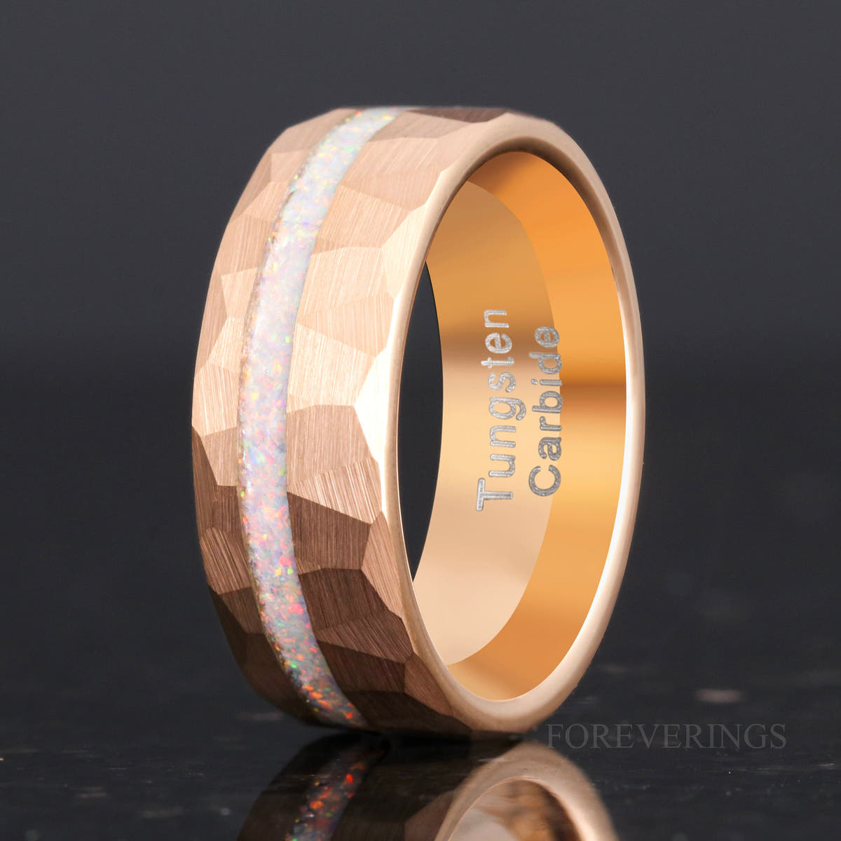 Men's 8mm hammered rose gold tungsten band with white fire opal inlay, standing at an angle