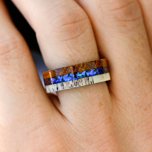 Men's 8mm black tungsten wedding band with whiskey barrel wood, antler and nebula sandstone, worn on a hand