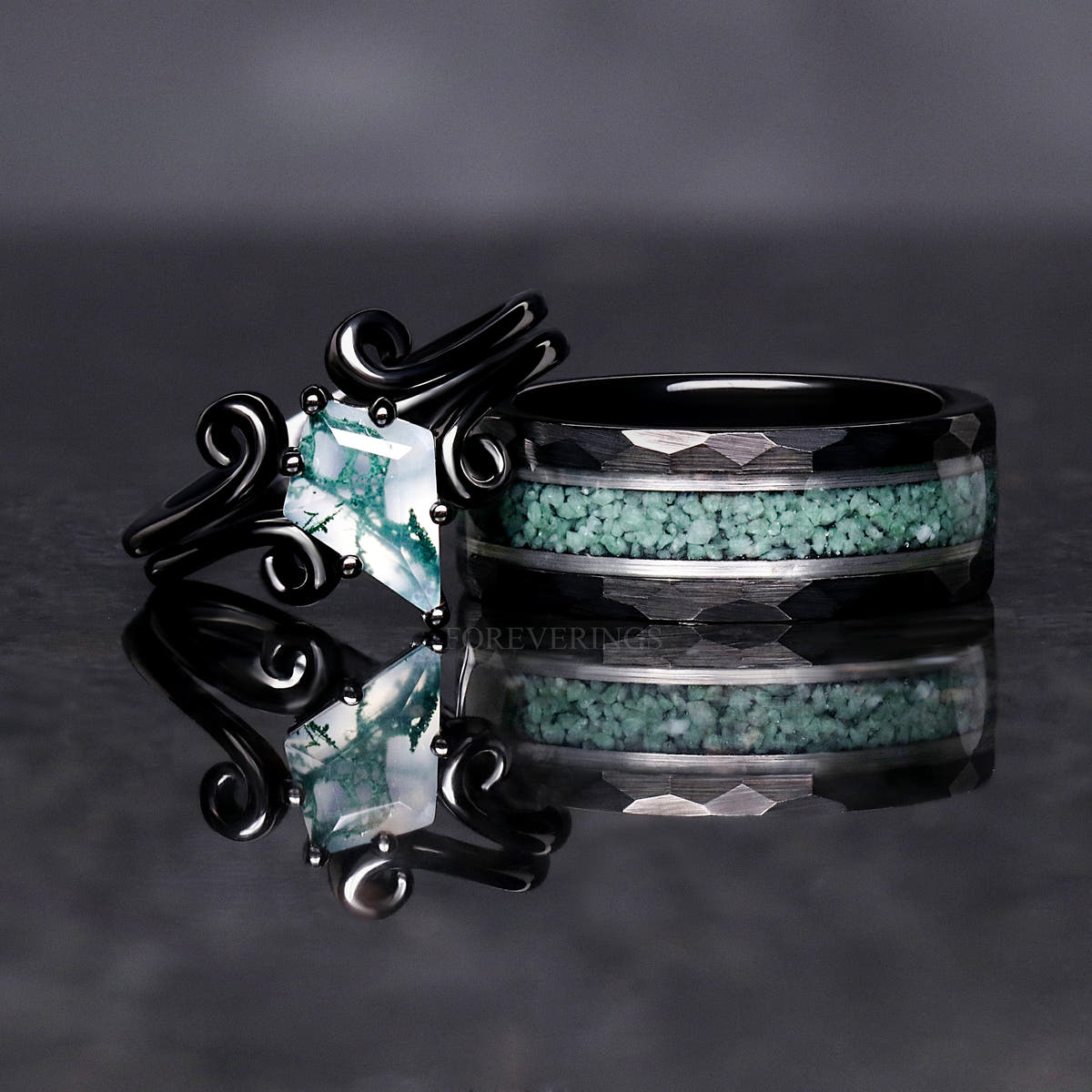 Moss agate ring in black sterling silver beside a hammered black tungsten moss agate band
