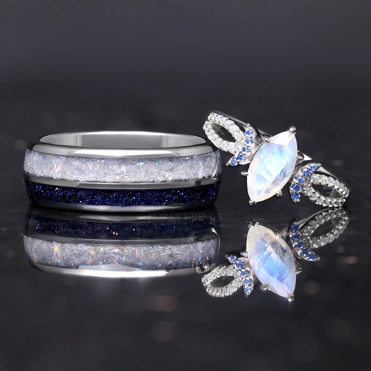 Marquise moonstone ring leaning on a wider silver tungsten band with moonstone and blue sandstone inlay