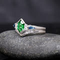 Women's sterling silver tsavorite bridal set at an angle, engagement ring nested in a curved band