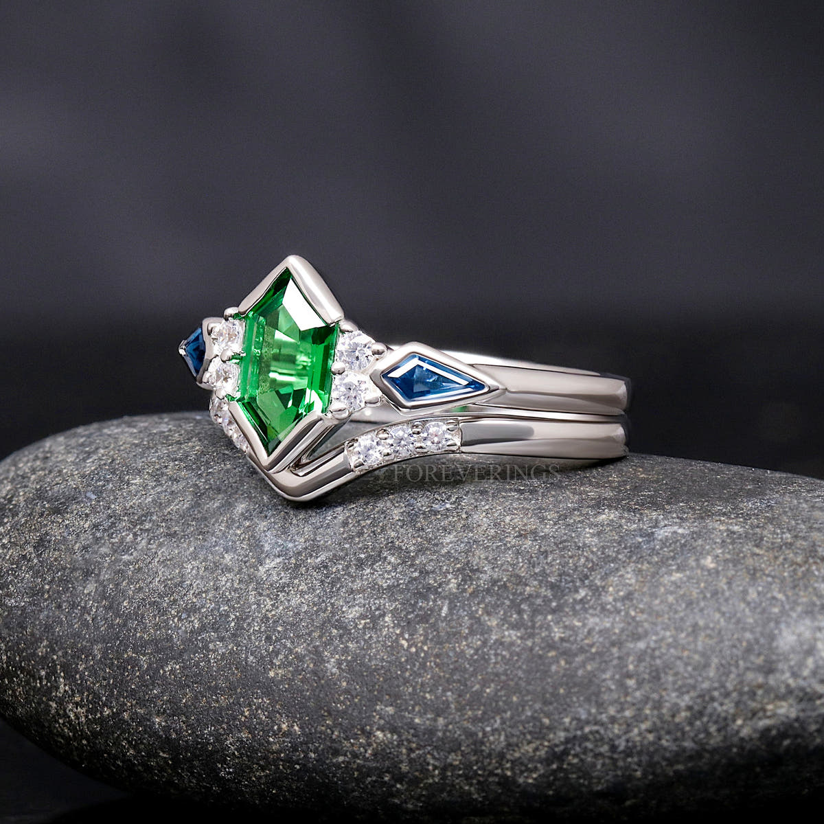 Women's sterling silver tsavorite bridal set at an angle, engagement ring nested in a curved band