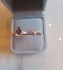 Gold amethyst engagement ring and wedding band with white accent stones in a gray velvet ring box